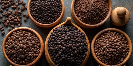 Miscele diverse di chicchi di caffè tostato in contenitori di legno.
